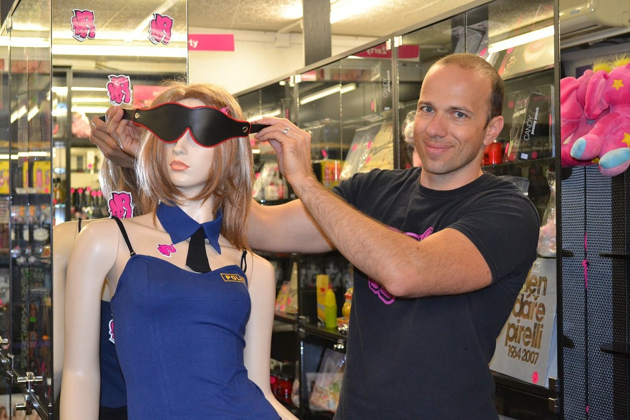 Adam předvádí koženou masku v prodejně na figuríně